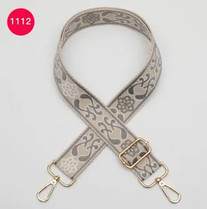 Detailed view of ethnic jacquard wide bag strap with gold metal hardware and adjustable buckle.