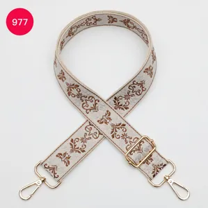 Detailed view of wide ethnic jacquard bag strap with adjustable gold metal hardware and clips.