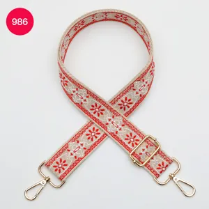 Vista detallada de la correa de bolso tejida de estilo étnico con patrón floral rojo y dorado.