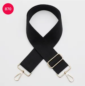 Détail en gros plan d'une large sangle de sac noire de rechange avec ferrures dorées robustes.