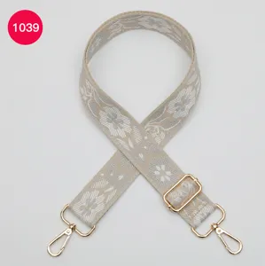 Detailed view of wide jacquard bag strap with ethnic floral pattern and gold hardware.