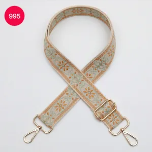 Primer plano de los detalles de la correa de bolso étnica de jacquard con broches dorados.