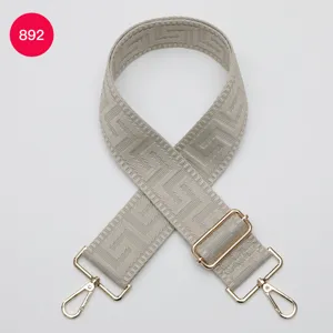 Wide adjustable woven bag strap with geometric labyrinth pattern and gold hardware.