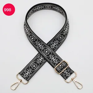 Detalle de correa de bolso jacquard étnico en blanco y negro con herrajes metálicos.