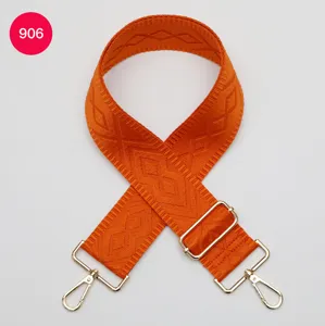 Large bandoulière de sac orange avec motif tissé géométrique et quincaillerie dorée réglable.