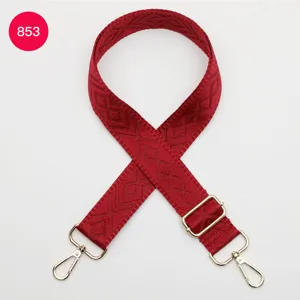 Dettaglio in primo piano della tracolla per borsa tessuta rossa con motivo geometrico e ganci.