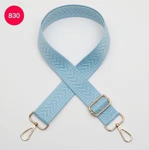 Bandoulière de sac tissée bleu clair avec des garnitures métalliques dorées réglables.