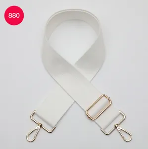 Vue détaillée de la large sangle de sac en toile blanche avec boucles métalliques dorées.