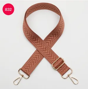 Vue détaillée de la bandoulière de sac tissée à chevron marron avec matériel doré.