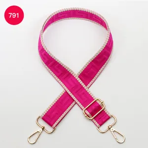 Adjustable pink woven bag strap with golden hardware, chic geometric maze pattern design accessory.