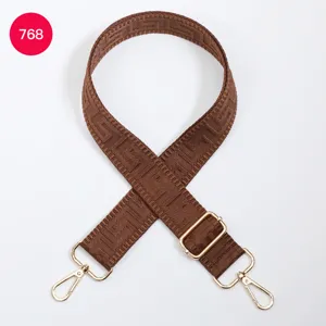 Brown woven bag strap detail with geometric maze pattern and golden metal adjustable hardware.