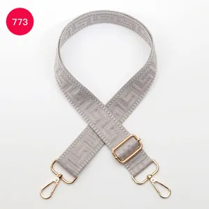 Close-up detail of gray woven bag strap featuring geometric pattern and gold hardware.