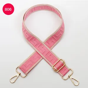 Pink geometric pattern wide bag strap with gold metal hardware clips and adjustable slider.
