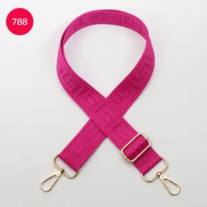Close-up of adjustable pink bag strap with geometric Greek key pattern and gold hardware.
