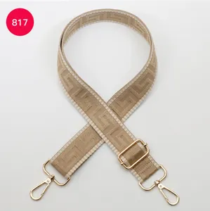 Detailed view of wide adjustable bag strap with gold metal hardware and geometric pattern.