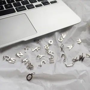 Silver alphabet letter charms detail shot, stylish sterling silver initial pendants close up.