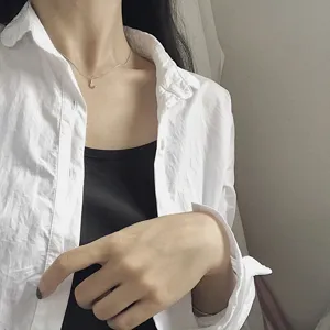 Detailed shot of a Korean style sterling silver letter J pendant necklace worn by model.