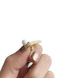 Élégantes boucles d'oreilles clous perle zircon forme J argent 925 style coréen sur main.