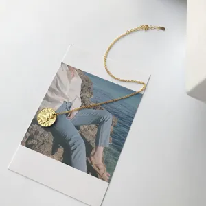 Close-up detail of the elegant gold coin pendant necklace displayed on an aesthetic postcard.