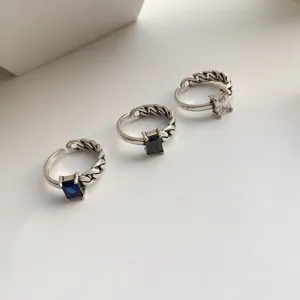 Gros plan de bagues ouvertes en argent sterling vintage avec des pierres carrees colorees.