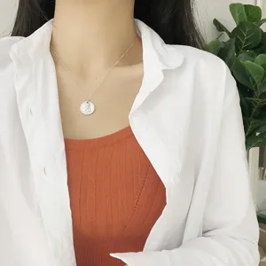 Silver coin pendant necklace detail shot worn by model, elegant minimalist jewelry style.