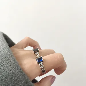 Gros plan détaillé de la bague chaîne rétro en argent avec pierre bleue, portée élégante.