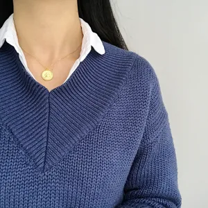 Detail close-up of a golden Elizabeth coin pendant necklace worn gracefully on the human neck.