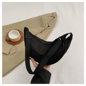 Detailed view of a black nylon crescent shoulder bag, featuring a stylish dumpling shape and strap.