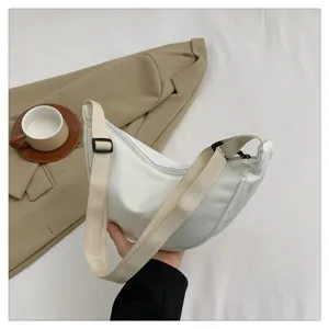 Detailed view of the white nylon crescent crossbody bag, highlighting the zipper and adjustable strap.