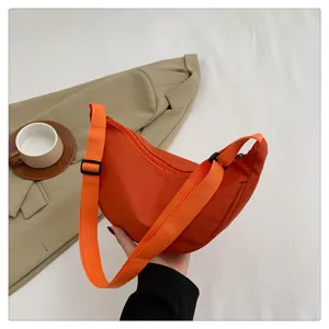 Orange nylon crescent crossbody bag detail, casual lightweight dumpling shoulder bag design.