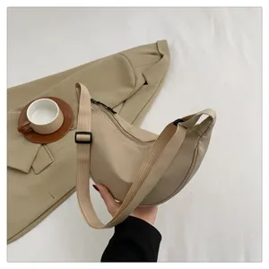 Detail view of beige nylon crescent dumpling hobo bag, lightweight sports style cross body.