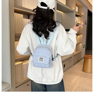 Detail view of mini corduroy backpack in light blue, showing front pocket and casual design.