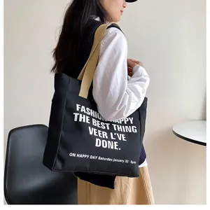 Casual black canvas tote bag with white letter print, large capacity commuter shoulder bag.
