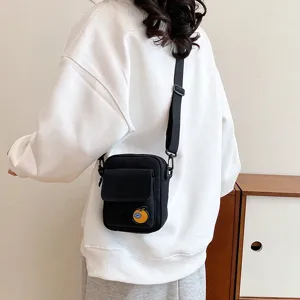 Detailed view of a cute black canvas crossbody phone bag with a sweet orange patch for daily use.