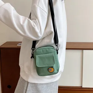 Green canvas crossbody bag detail, cute orange patch design, mini shoulder phone bag for girls.