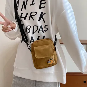 Detail view of a cute canvas crossbody phone bag in brown with a sweet orange badge.