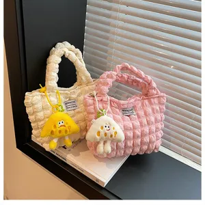Detalle de bolso de mano acolchado estilo coreano con tela arrugada suave y bonito colgante.