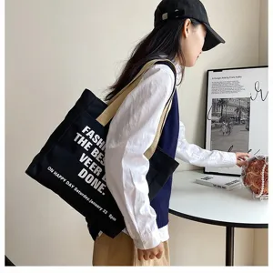 Detailed view of black canvas tote bag showcasing large capacity and stylish printed text.