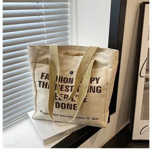 Canvas tote bag detail showcasing durable beige fabric, sturdy shoulder straps and print.