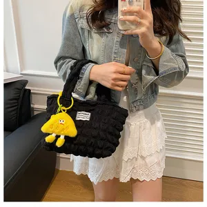 Bolso de mano negro plisado tipo burbuja con bonito colgante de peluche amarillo uso.