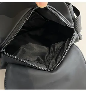 Detalle interior de bolso bandolera de nailon impermeable negro con bolsillo con cremallera.