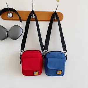 Detail view of cute canvas crossbody bags in red and blue with orange patch for kids and girls.