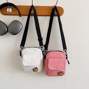 Detailed shot of cute canvas messenger bags in white and pink, hanging on a wall hook.