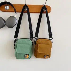 Canvas phone bag detail showing adjustable strap and cute orange badge design.