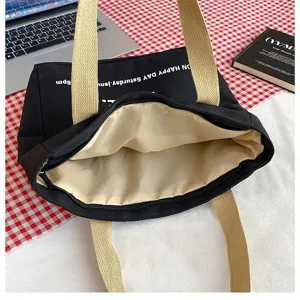 Black canvas tote bag detail view, zipper closure, beige straps, casual daily use style.