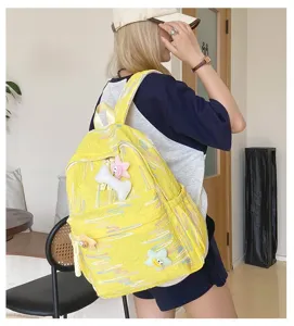 Gros plan d'un sac à dos jaune tendance doté de charmants pendentifs en peluche pour l'école.