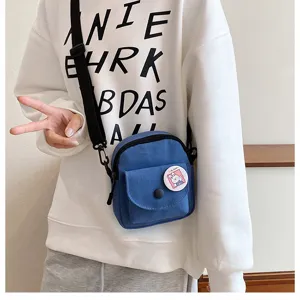 Vue détaillée de la poche avant du sac bandoulière en toile et badge lapin, style casual.