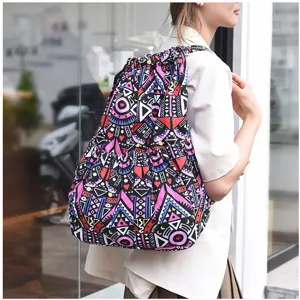 Vue détaillée d'un sac à dos cordon en toile à motif géométrique coloré porté.