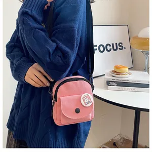 Détail en gros plan du sac bandoulière en toile rose avec joli badge et fermeture éclair.