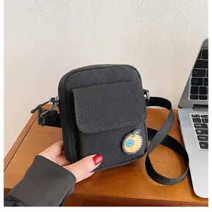 Black canvas crossbody small bag with cute fruit badge and adjustable shoulder strap detail.